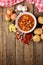 View from above of potato and sausage goulash, pepper, onion and garlic on wooden table and red dish-cloth vertical photo