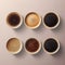 The view from above of several cups of coffee of various varieties being served.