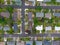 View from above. Small suburb. Small houses, paved roads, many parked cars near the houses. Residential area, lots of greenery,