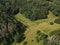 View from above of trees in the forest with a grassfield in the middle