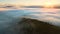 View from above of vibrant landscape of foggy woods with pine trees covering mountain hills at sunrise.