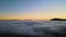 View from above of vibrant landscape of foggy woods with pine trees covering mountain hills at sunrise.