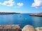 View across the bay in cala santandria menorca with old military ruins looking out on to bright blue sea