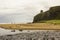 A view across Downhill beach in County Londonderry in Northern Ireland with a train heading toward Mussenden Temple