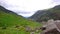 View across fields and valley towards base of mountain on PYG trail on Mount Snowdon in Snowdonia National Park, Wales, UK