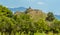 A view across an orchard to a hill top ruin in the foot hills of Mount Etna, Sicily