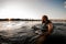 view of adult man in swimming vest swims in the water leaning on wakeboard