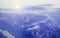 View from the aircraft on the Alps. Breathtaking view of dawn and mountain peaks in the snow, purple tinted and highlights in the