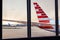 View of airplane fuselage tail through window at airport