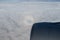 View from the airplane porthole. Blue sky, bright rainbow with the shadow of the plane.