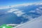 View from airplane porthole. blue sky, sea, coast, wing of plane