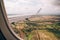 View from the airplane window of the fields and green meadows below