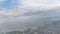 View from airplane window showing houses, buildings, clouds, mountains, skyline, ocean