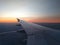 View from airplane window to beautiful sunrise or sunset. Wing of plane flying above in the sky