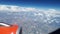 View from the airplane window to the blue sky and white clouds, an orange turbine on the wing of the plane, a view of