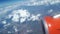 View from the airplane window to the blue sky and white clouds, an orange turbine on the wing of the plane, a view of