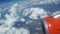 View from the airplane window to the blue sky and white clouds, an orange turbine on the wing of the plane, a view of