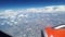 View from the airplane window to the blue sky and white clouds, an orange turbine on the wing of the plane, a view of