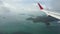 View through an airplane window on the tropical island, ocean, sky and clouds