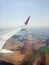 view from airplane window with wing, above agricultural field and dam