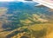 View of airplane wing, blue skies and green land during landing. Airplane window view