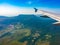 View of airplane wing, blue skies and green land during landing. Airplane window view