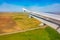 View of airplane wing, blue skies and green land during landing. Airplane window view