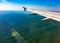 View of airplane wing, blue skies and green land during landing. Airplane window view