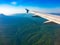 View of airplane wing, blue skies and green land during landing. Airplane window view