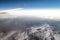 View from airplane with a wing and a folded terrain covered with snow and glaciers in the Iranian highlands