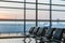 View of airport interoir, empty bench chairs in the departure hall during sunrise. Airplane and building background