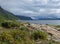 View on Akkajaure lake with green mountains, rock boulders, bushes, birch tree and dramatic clouds