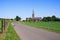 View along agricultural path over green fields on  neo-gothic church in countryside