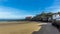 A view along the harbour wall towards the Castle Hill and the Lifeboat Stations in Tenby bathed in sunshine at low tide