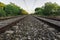 View along the railway. Old railroad across the bridge. The road for the train on the sides of the green vegetation and forest