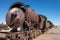 A view along the side of a rusting steam train and carriages slowly rot away at the train graveyard just outside of Uyuni, Bolivia