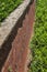 View alongside tall brick retaining wall with rusticated stone cap, green shrubbery