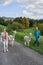 View of alpacas walking with Caucasian women in greenery field