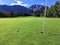 A view of an amazing shot with a golf ball on a green close to the hole with the mountains and forest in the background