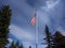 View of an American flag, flapping in the wind near evergreen trees in the pacific northwest