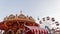 View of the amusement park with a colorful vintage carousel with bright lights and a ferris wheel. Great joyful weekend.