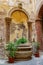 A view of the antique fountain in the courtyard decorated with a pulley and a chain of hanging ferns