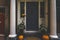 View of a apartment exterior door and decoration of plants and pumpkins for Thanksgiving. Stoop with building columns