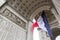 View of Arc de Triomp with flag of France waving in wind on Place de Gaulle in Paris, France