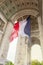 View of Arc de Triomp with flag of France waving in wind on Place de Gaulle in Paris, France