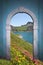 View through arched door; alpine lake and mountains