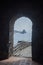 View from arched stone door in Norman castle Aci Castello to small rocky islands near Catania, Sicilia, Italy