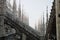 View of architectural detail of Duomo di Milano roofs. Foogy morning. Gloomy gothic