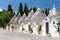 View of architectures with cone roofs made of small stones in Alberobello, Italy