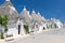 View of architectures with cone roofs made of small stones in Alberobello, Italy